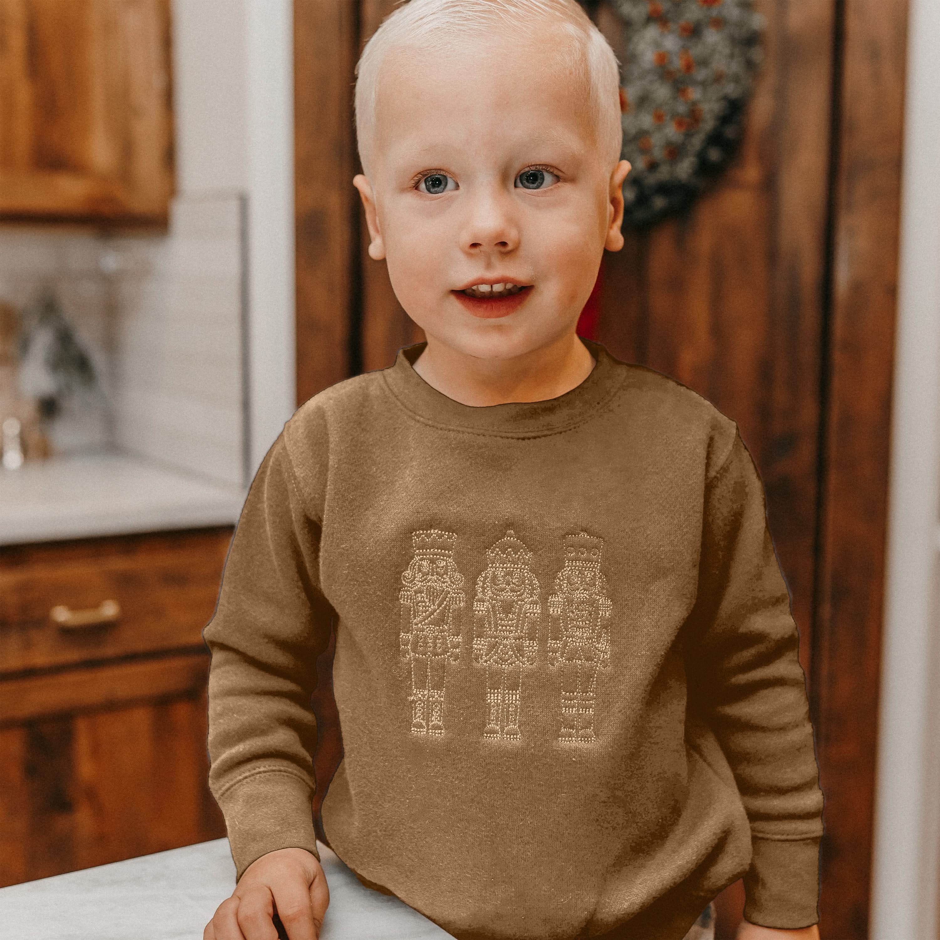 Child sweater in navy with 3 embroidered nutcrackers on chest, shown on model – Little Mama Shirt Shop