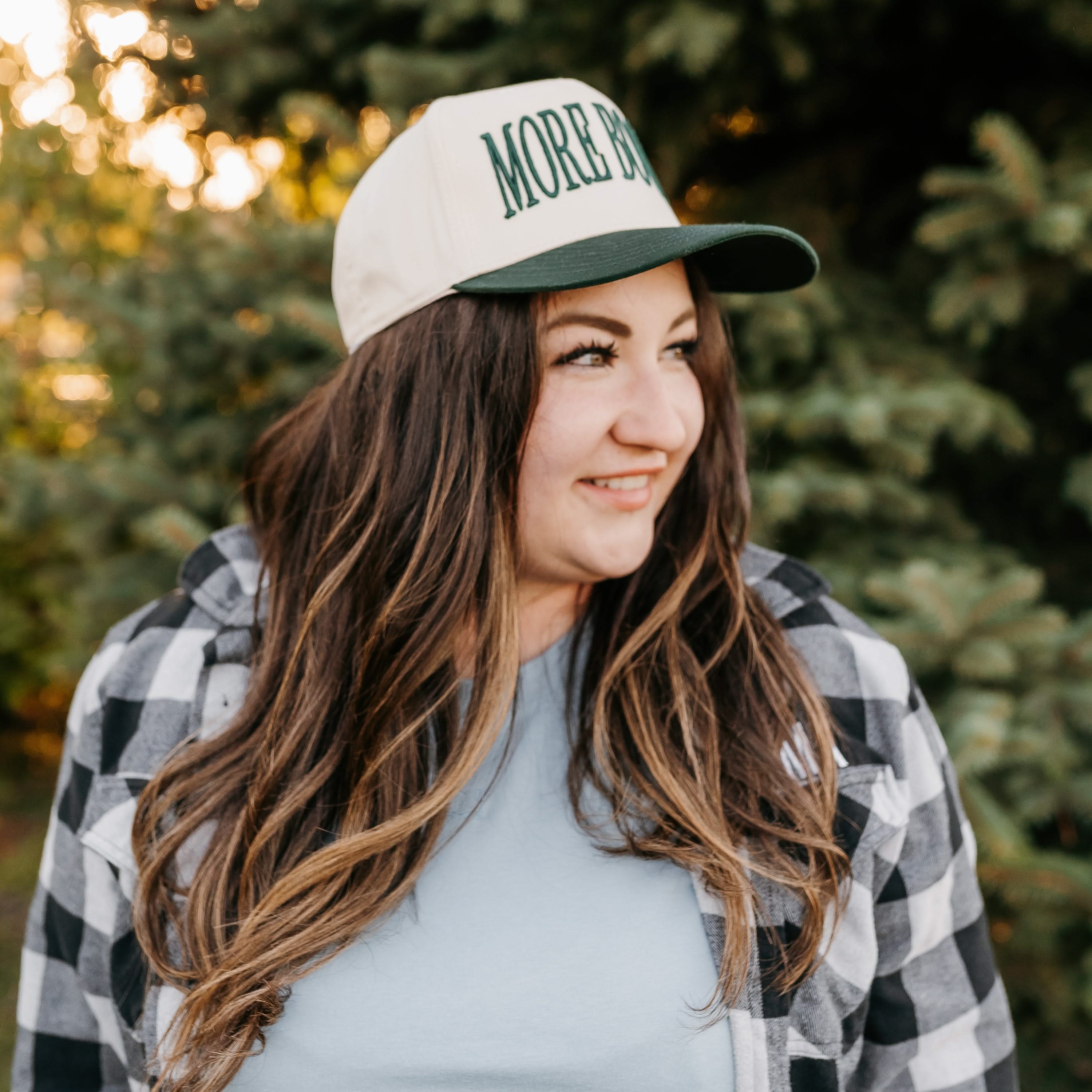 Tan and green trucker hat with adjustable closure, featuring a front embroidered design that reads “More Books" on model - Little Mama Shirt Shop