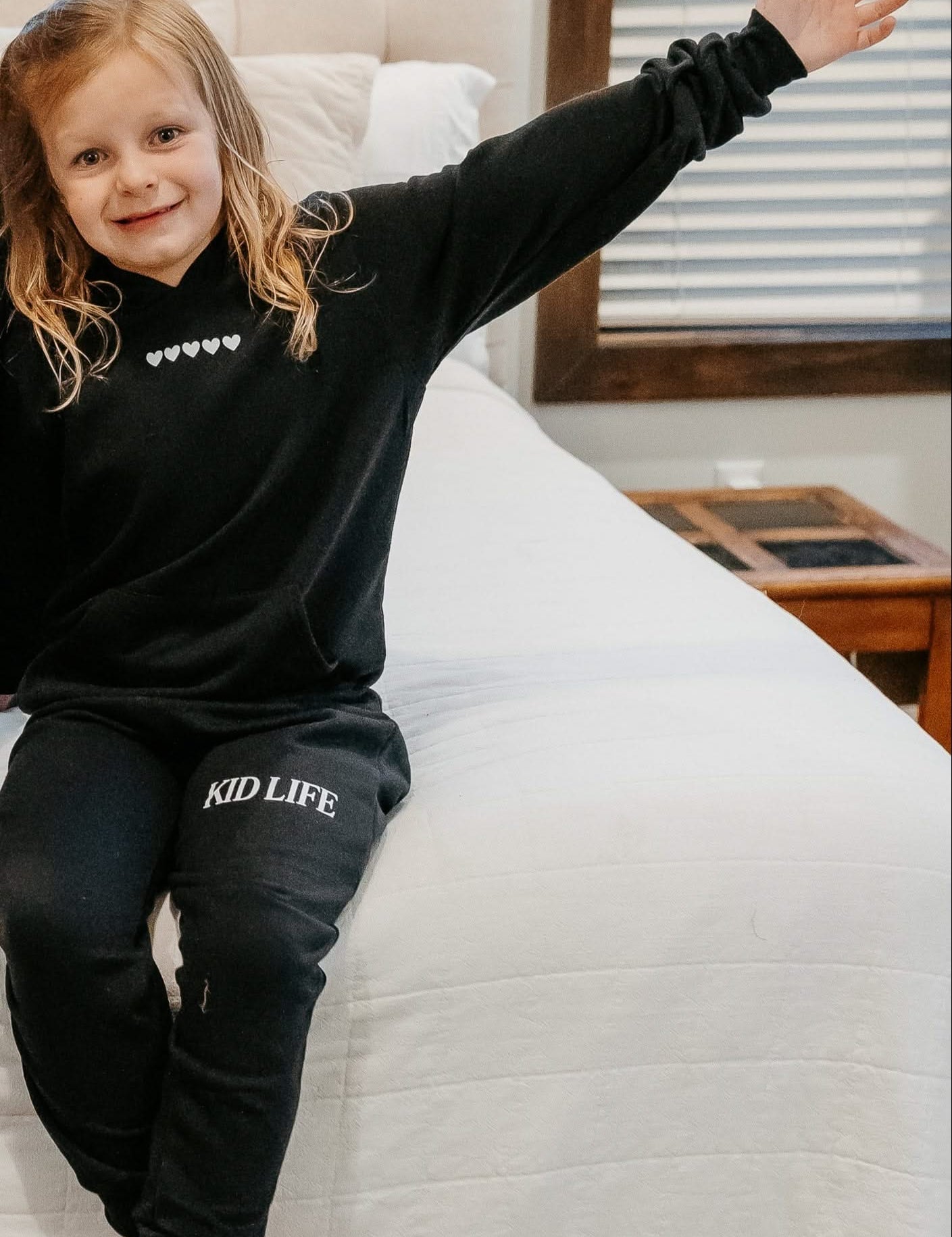 Kids hoodie and jogger in black with white hearts on chest and 'Kid Life' on leg of joggers on model - Little Mama Shirt Shop