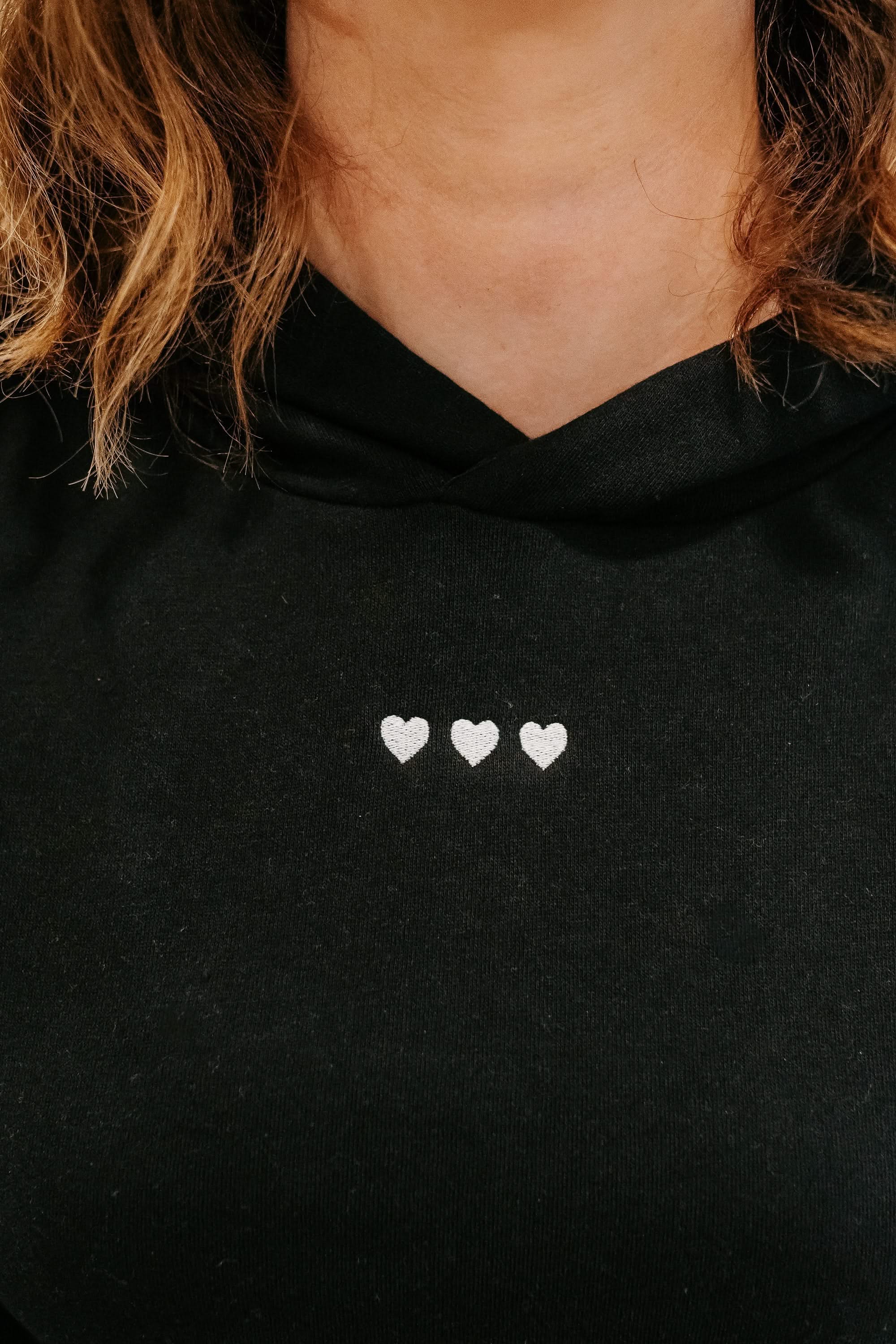 Hoodie chest close up black with white with three embroidered hearts on model - Little Mama Shirt Shop