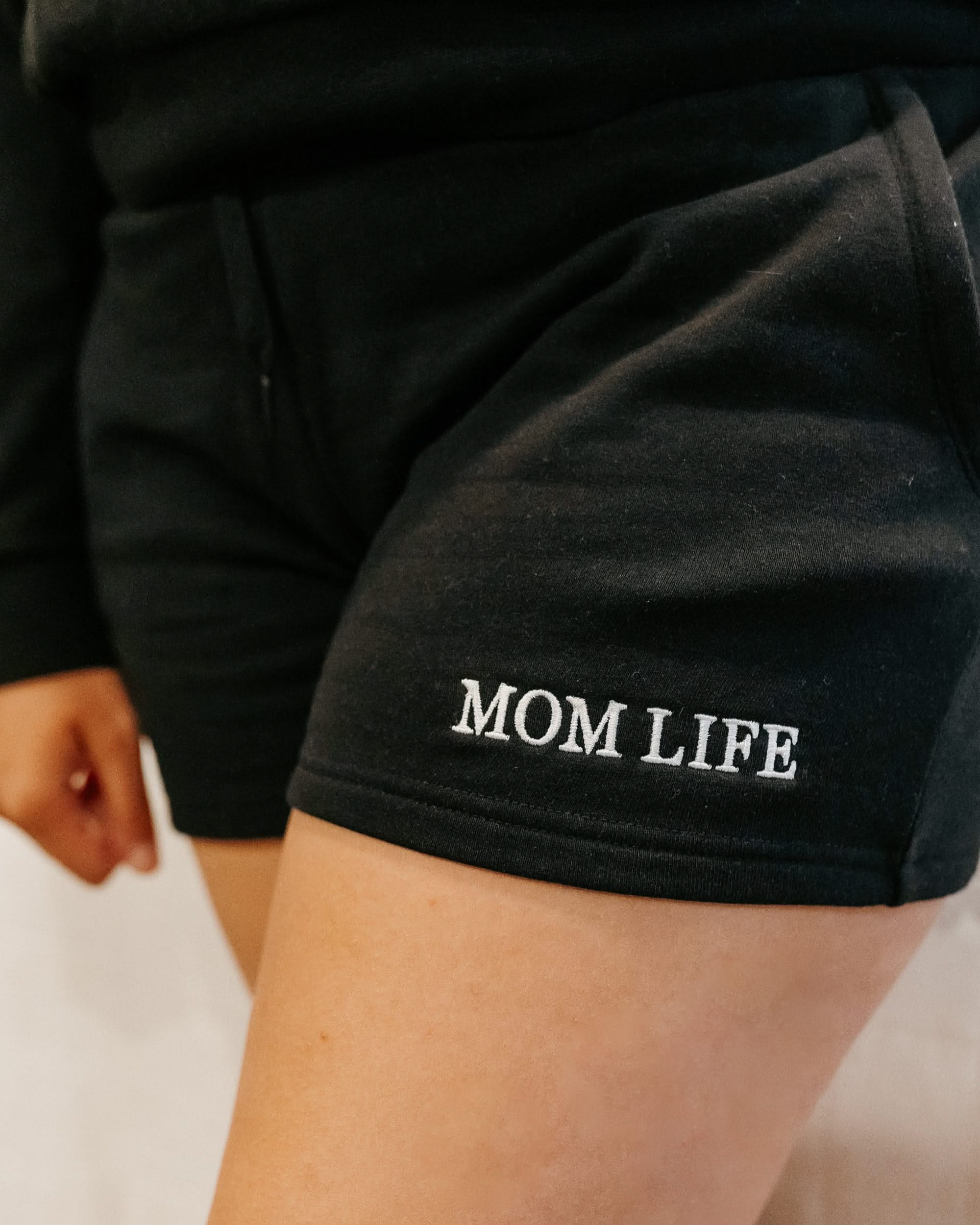 Short close up in black with white embroidered  'Mom Life' graphic on model - Little Mama Shirt Shop
