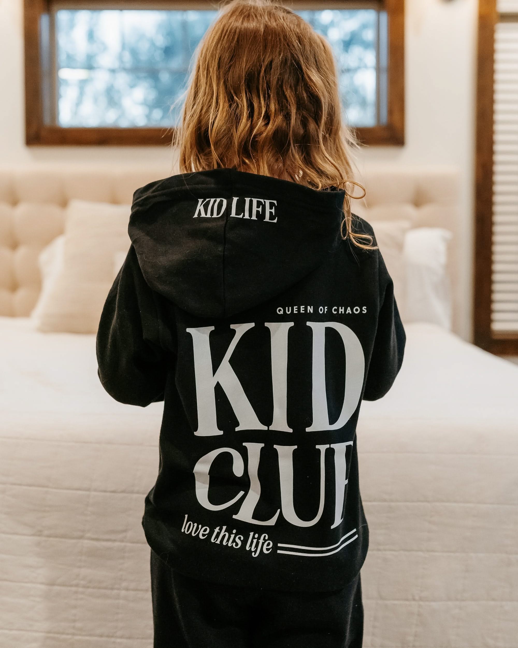 Hoodie back view in black with white 'Kid Club' graphic on model - Little Mama Shirt Shop