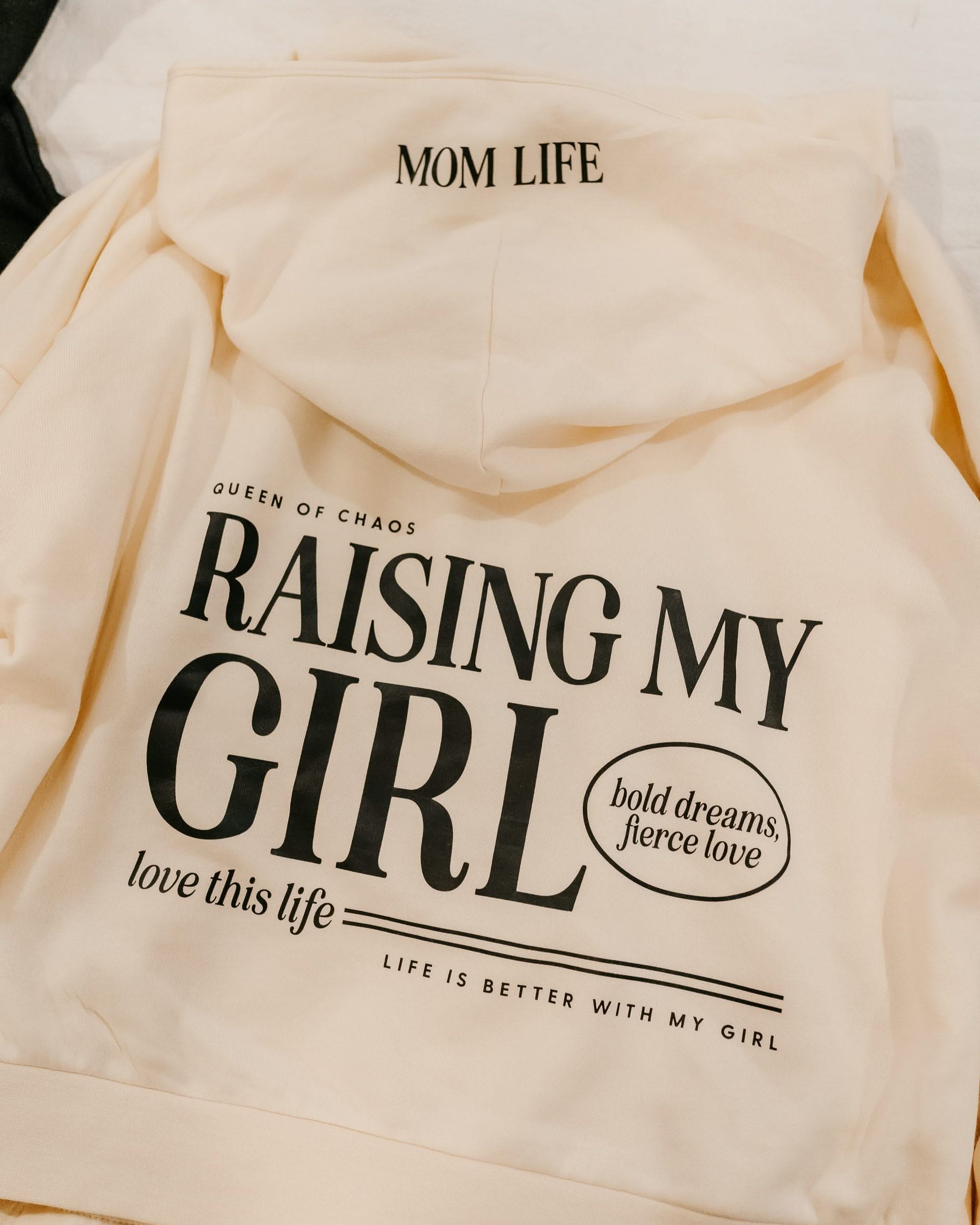 Hoodie in bone with black 'Raising My Girl' graphic on flat lay - Little Mama Shirt Shop