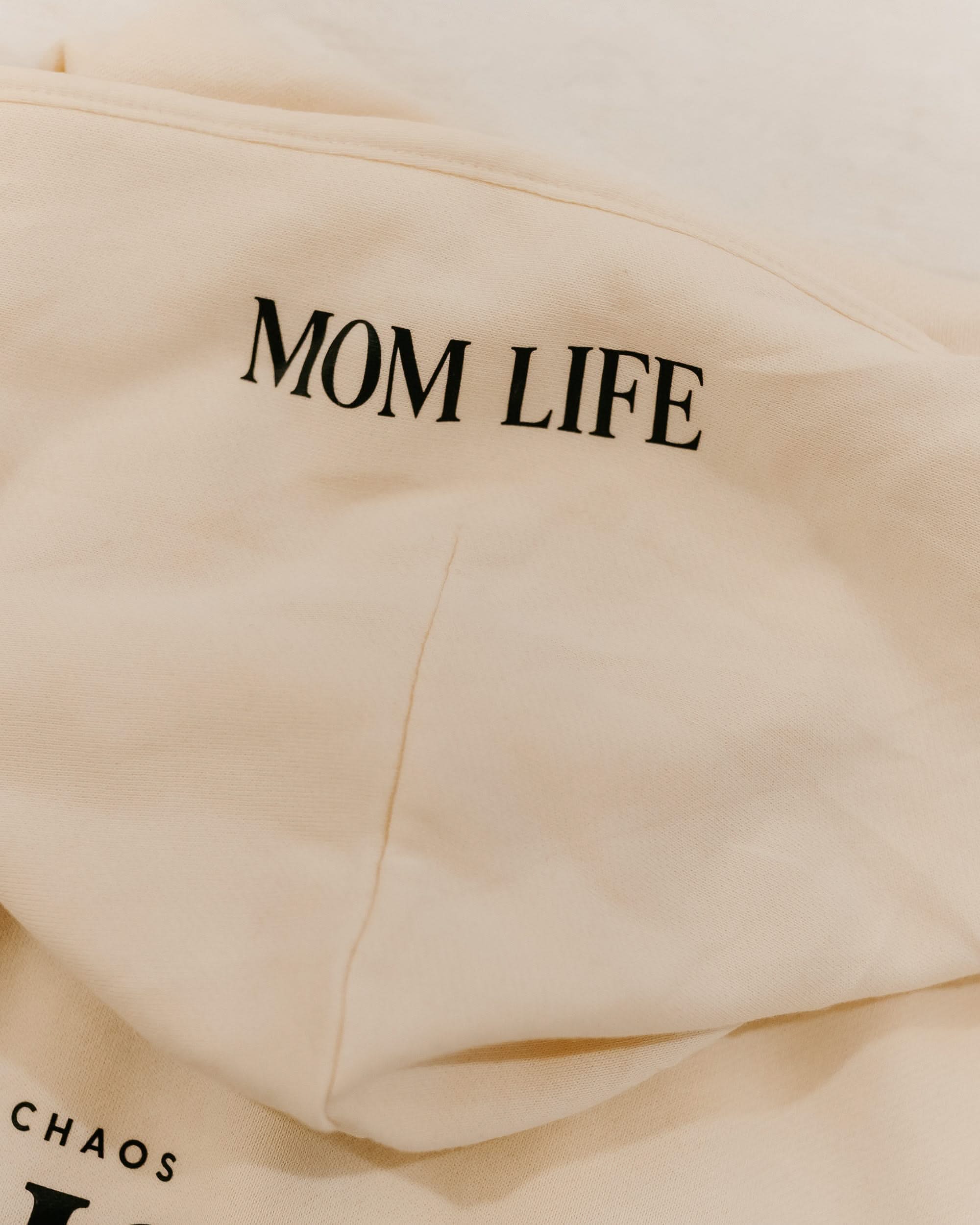 Hoodie in bone with black close up on hood with 'Mom Life' graphic on flat lay - Little Mama Shirt Shop
