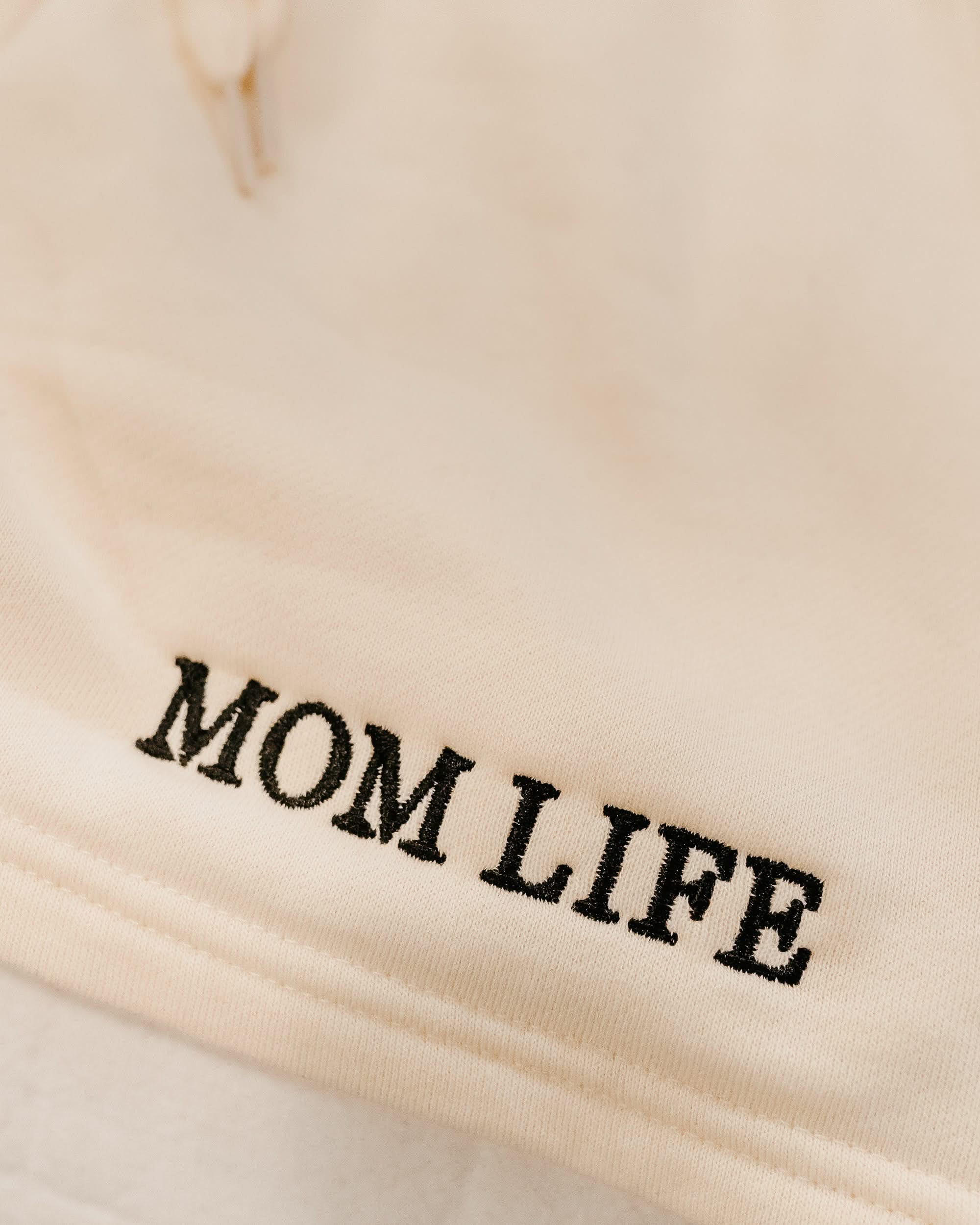 Short close up in bone with black embroidered  'Mom Life' graphic on model - Little Mama Shirt Shop