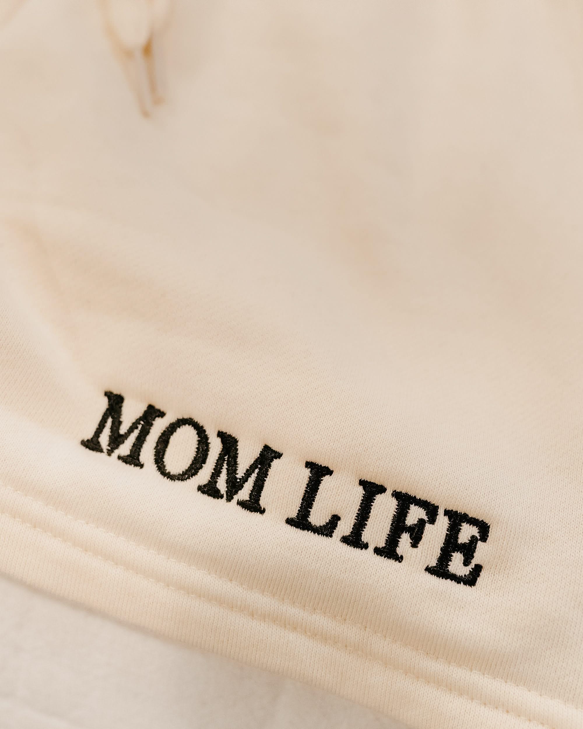 Short close up in bone with black embroidered  'Mom Life' graphic on model - Little Mama Shirt Shop