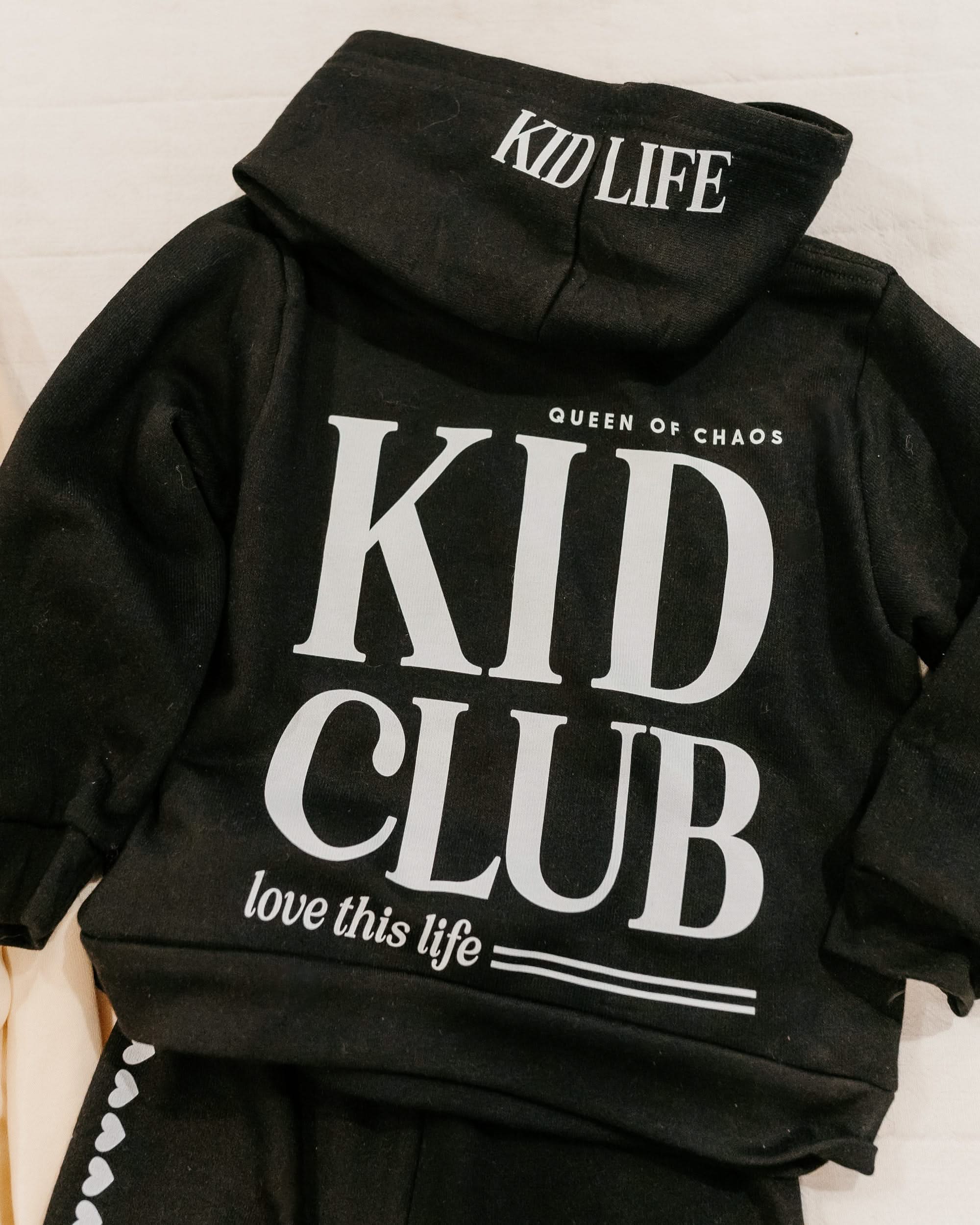 Hoodie back view in black with white 'Kid Club' graphic on flat lay - Little Mama Shirt Shop
