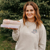 Unisex “Lose Yourself, Find Yourself” sweatshirt in pigment sand with embroidered book stack on model – Little Mama Shirt Shop