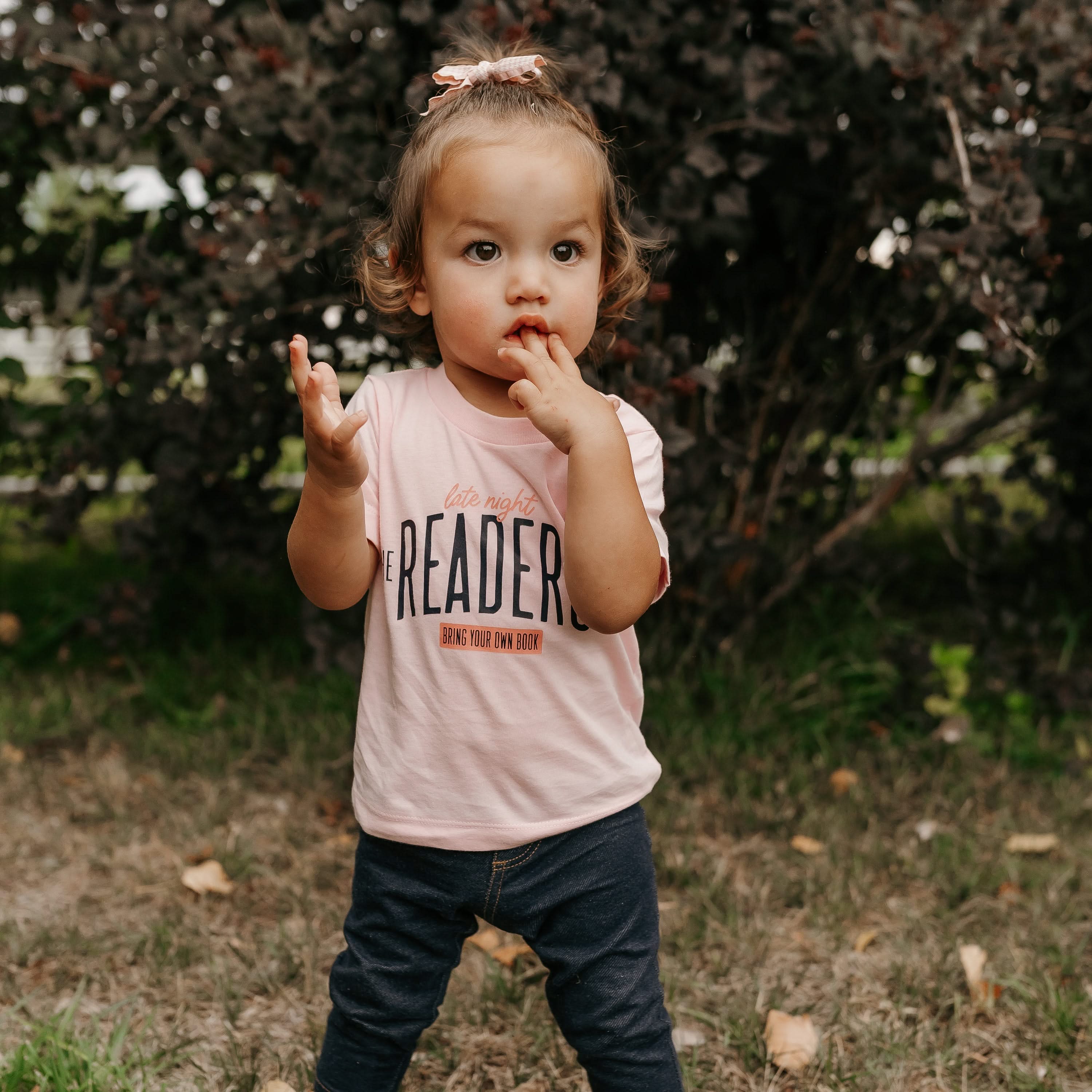 Child’s t-shirt with “Late Night Readers Club BYOB” design in pink, on model – Little Mama Shirt Shop