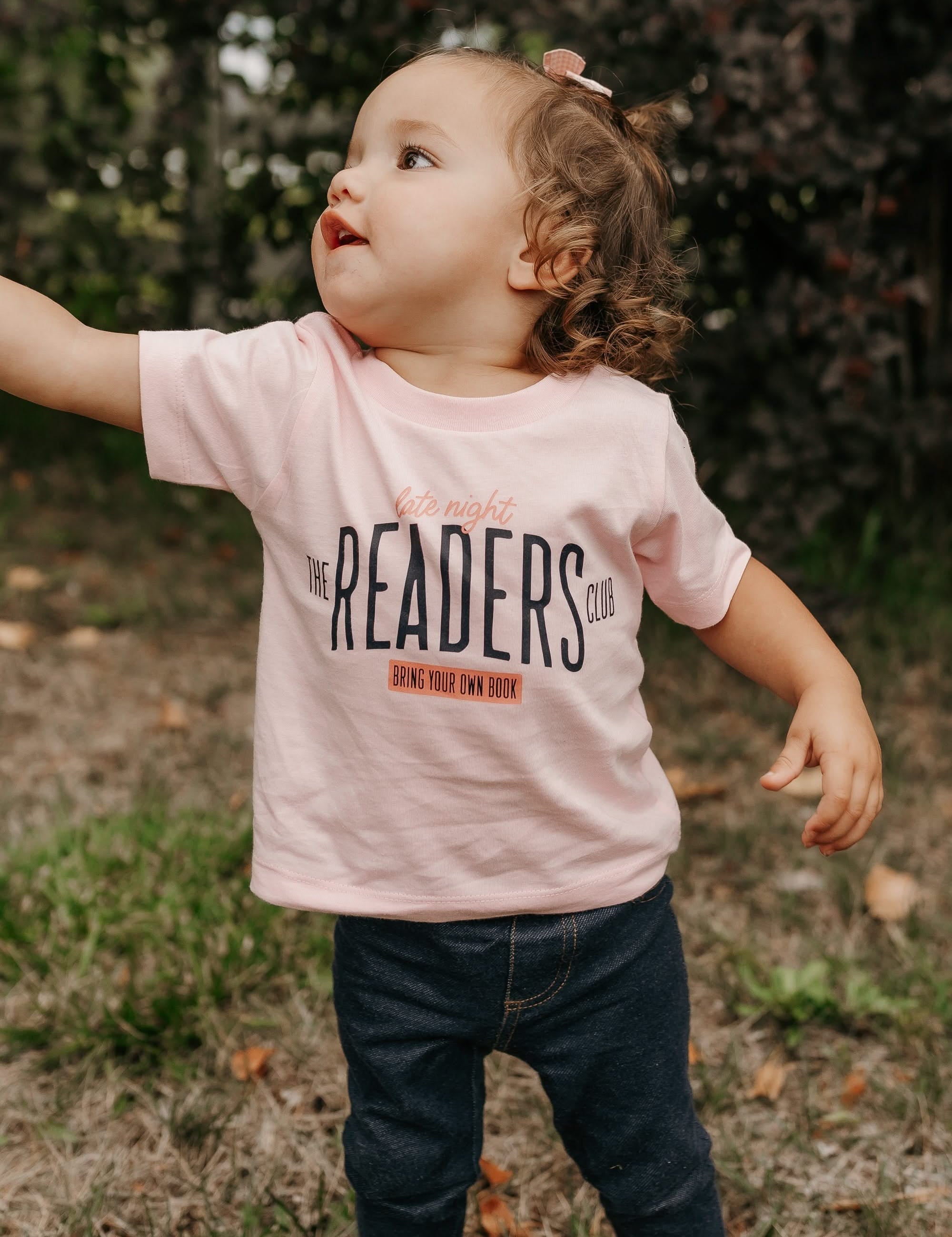 Child’s t-shirt with “Late Night Readers Club BYOB” design in pink, on model – Little Mama Shirt Shop
