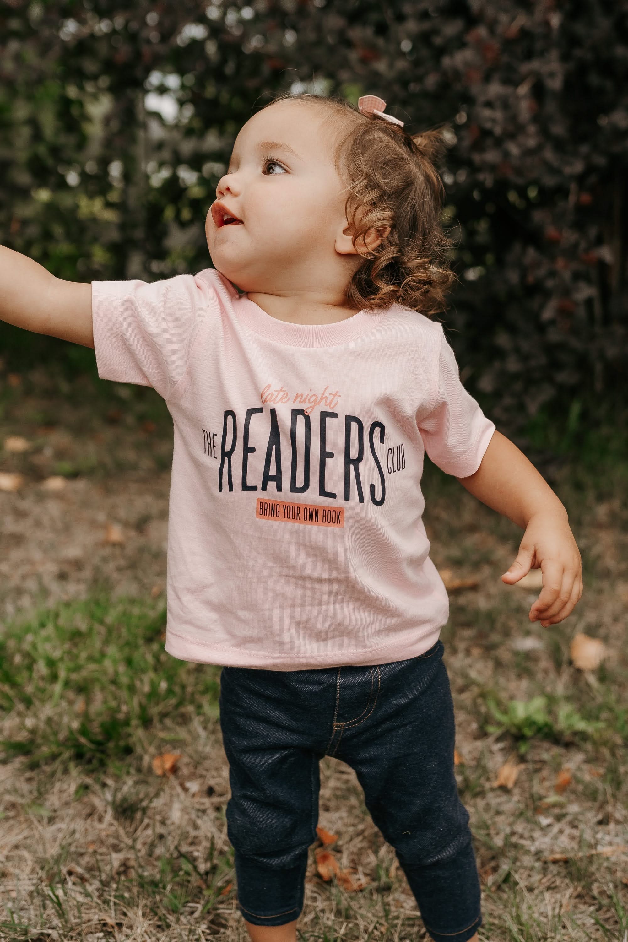 Child’s t-shirt with “Late Night Readers Club BYOB” design in pink, on model – Little Mama Shirt Shop