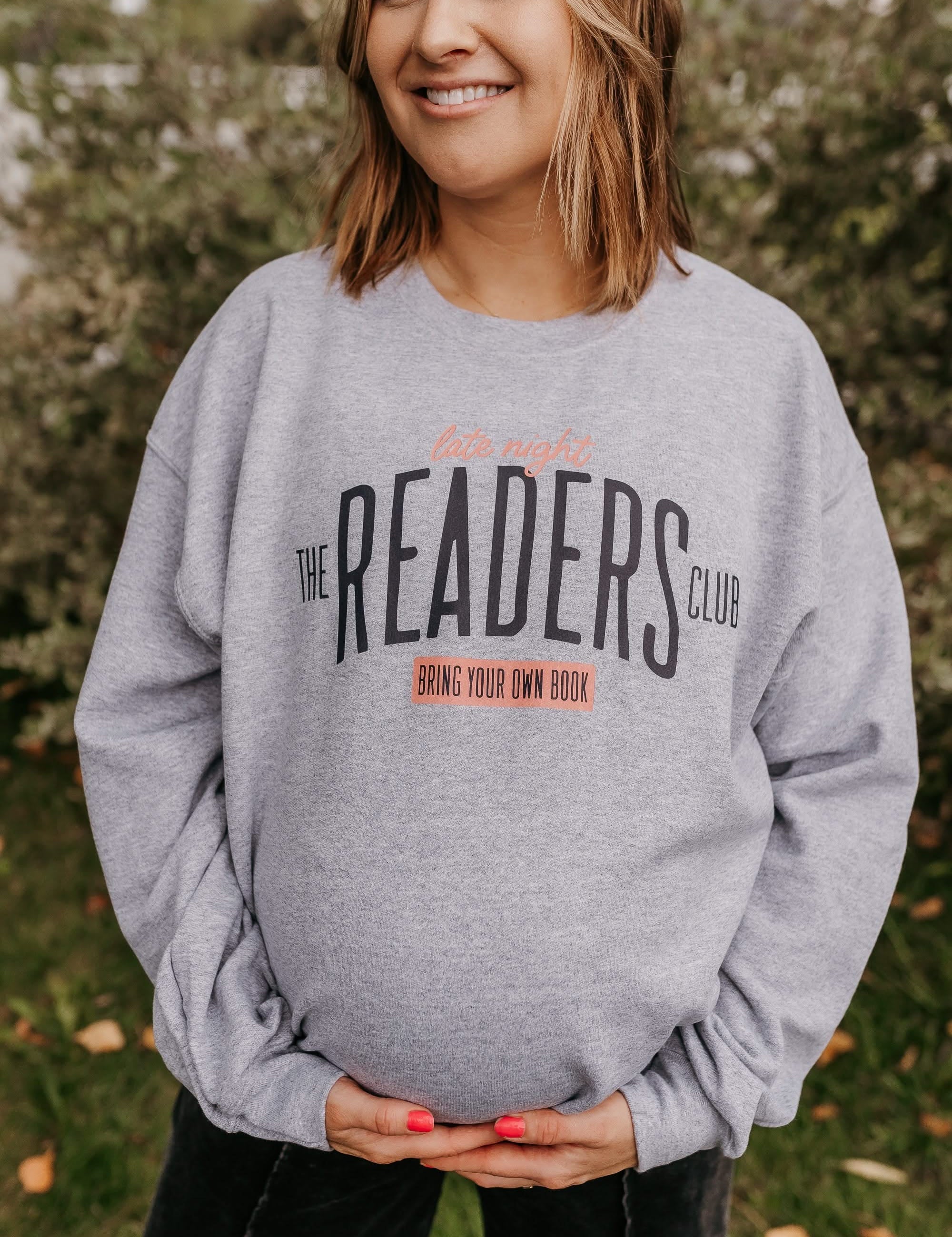 Unisex fleece sweatshirt in gray with “Late Night Readers Club BYOB” design on model – Little Mama Shirt Shop