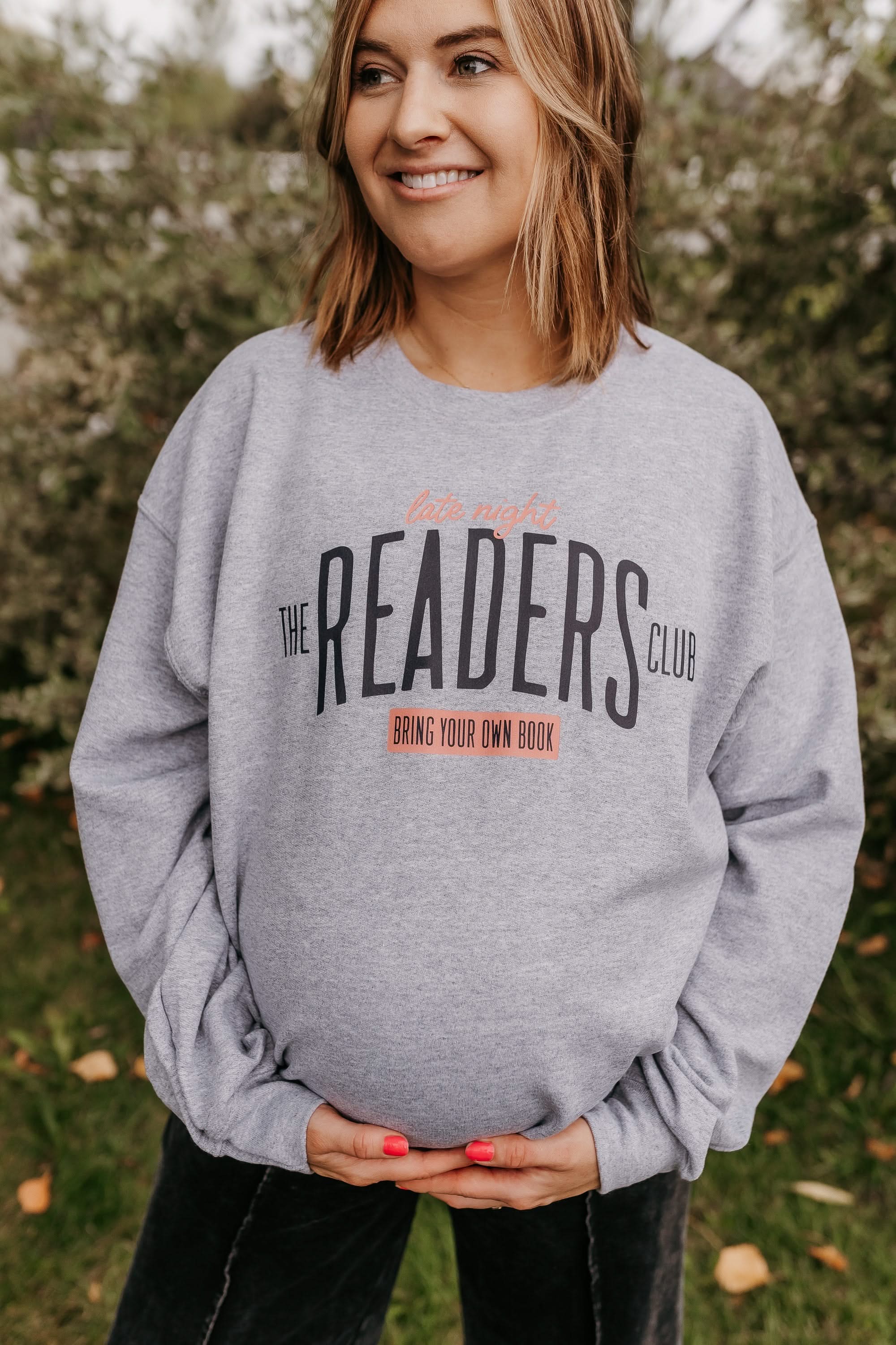 Unisex fleece sweatshirt in gray with “Late Night Readers Club BYOB” design on model – Little Mama Shirt Shop