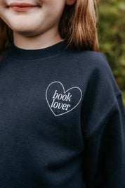 Child sweater in navy w/ light blue detail with a 'book lover' heart graphic on the front and 'What are you reading?' graphic on back, shown on model – Little Mama Shirt Shop