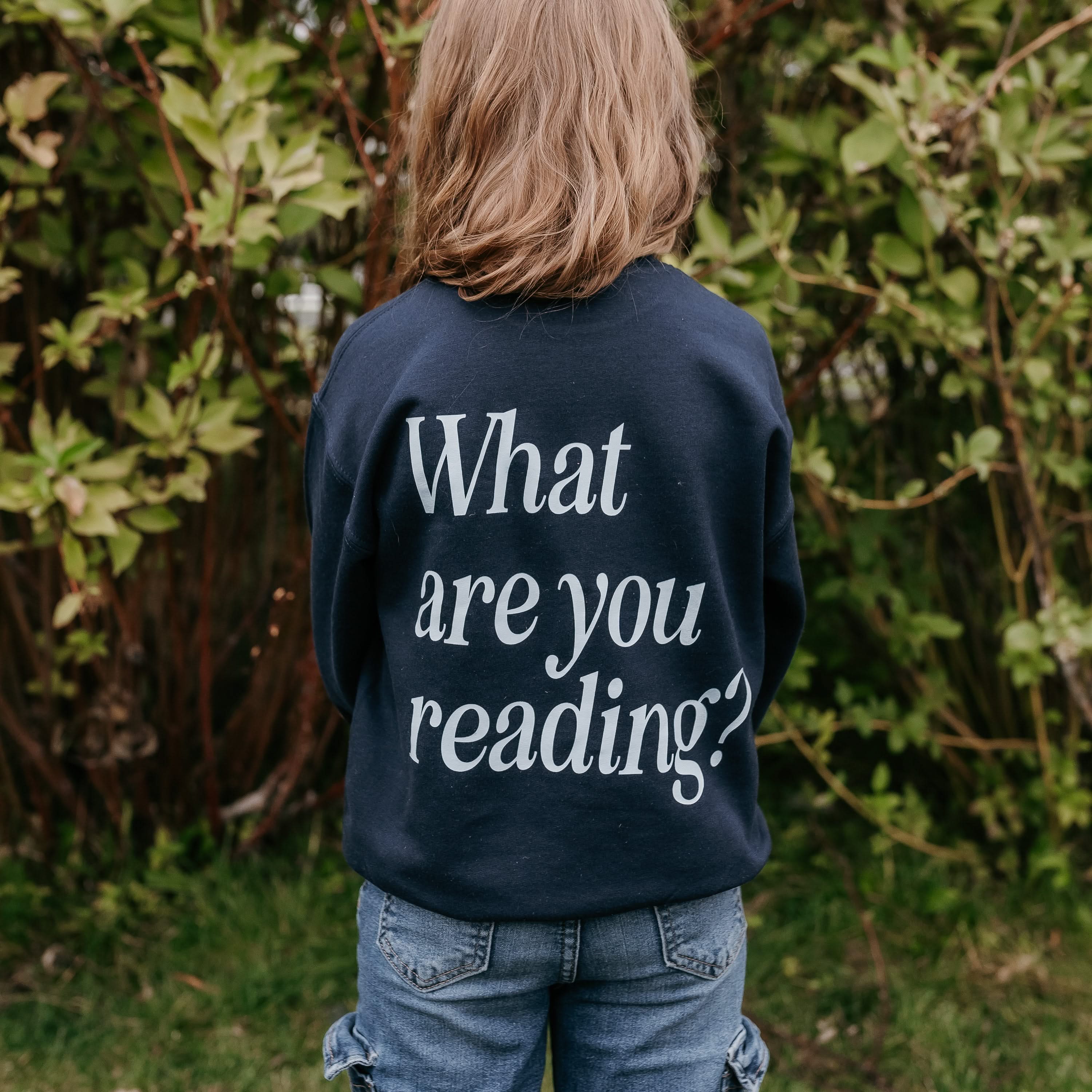  light blue detail with a 'book lover' heart graphic on the front and 'What are you reading?' graphic on back, shown on model – Little Mama Shirt Shop