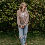 Unisex hoodie in brown savana with 'BOOKED' arched text on model – Little Mama Shirt Shop