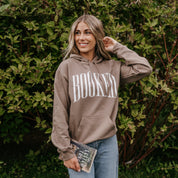 Unisex hoodie in brown savana with 'BOOKED' arched text on model – Little Mama Shirt Shop