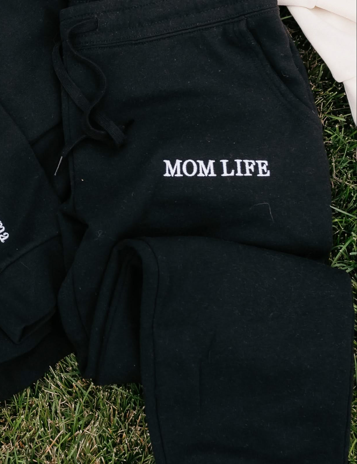 Joggers in black and white with 'Mom Life' embroidery on flat lay - Little Mama Shirt Shop