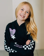 Child black sweater with checkers pattern on arm, and Purple Heart with 'be you' in it flanked by a white star, seen on model - Little Mama Shirt Shop