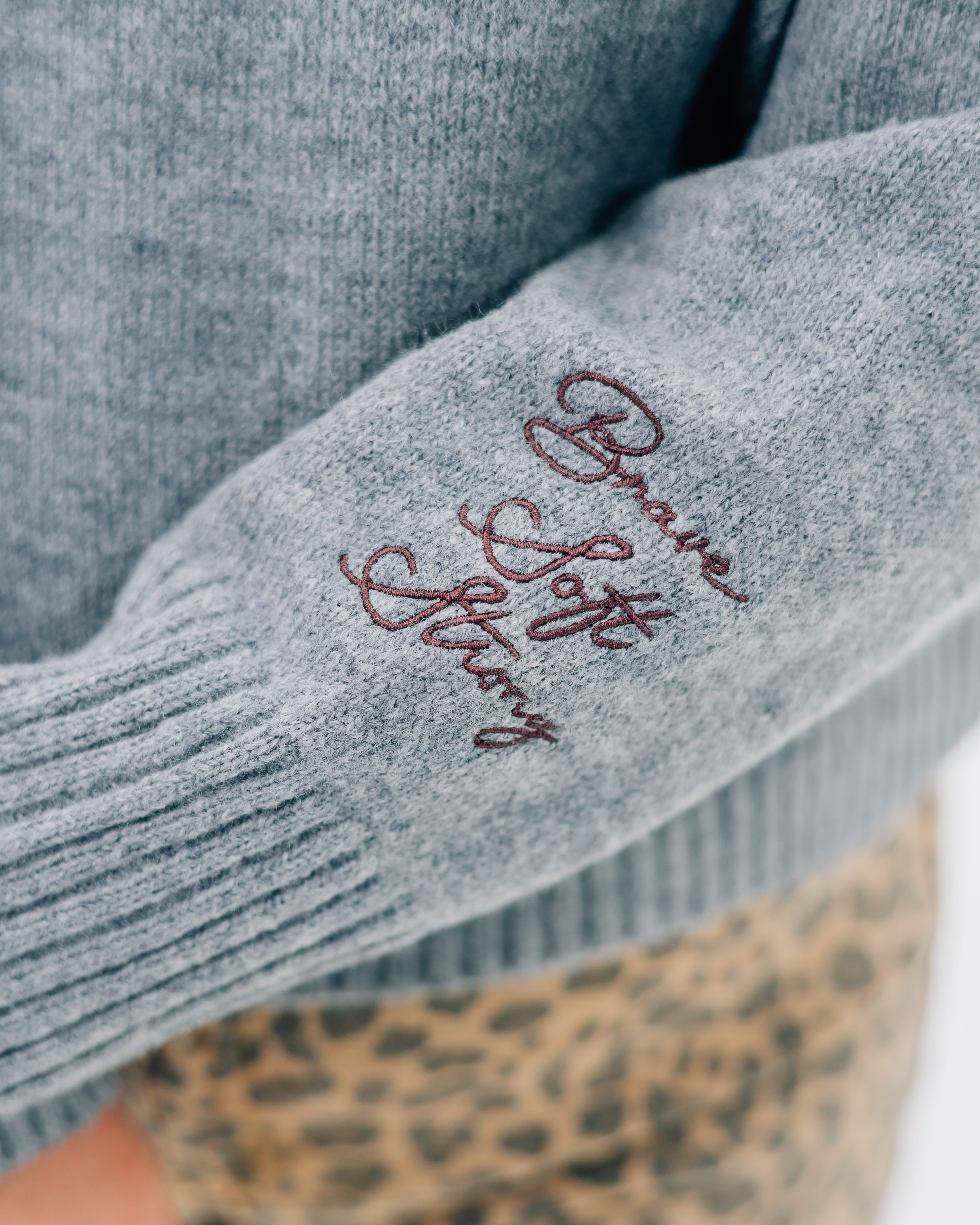 Gray sweater with "Brave, Soft, Strong" embroidered on the sleeve, seen on model - Little Mama Shirt Shop