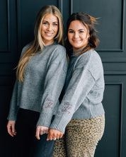 Gray sweater with "Brave, Soft, Strong" embroidered on the sleeve, seen on models - Little Mama Shirt Shop