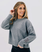 Gray sweater with "Brave, Soft, Strong" embroidered on the sleeve, seen on model - Little Mama Shirt Shop