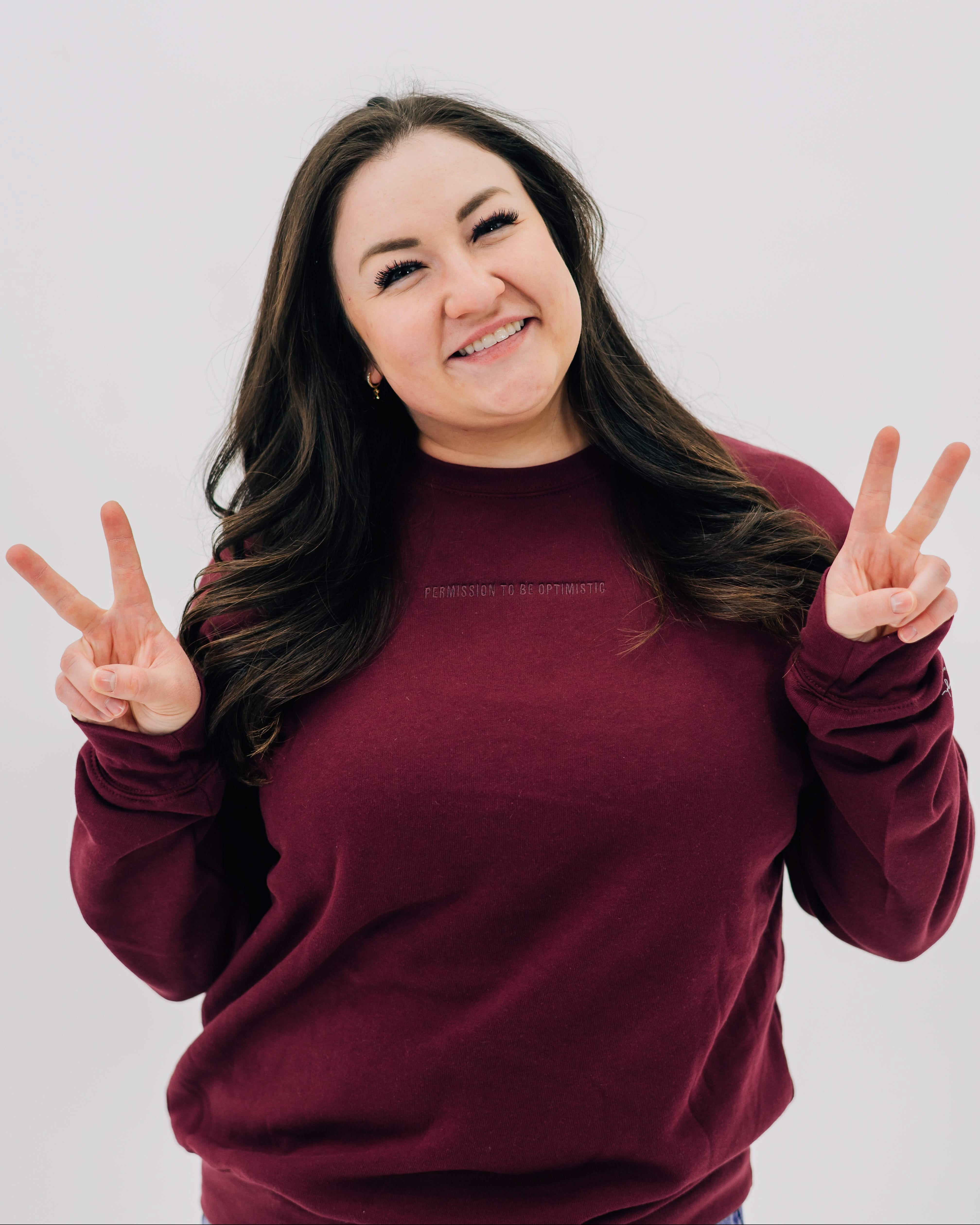 Maroon crewneck with "Permission To Be Optimistic" on chest, shown on model - Little Mama Shirt Shop