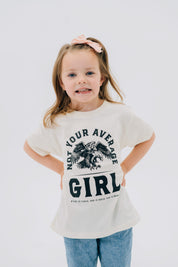Child tee in natural with "Not Your Average" design on front, shown on model  – Little Mama Shirt Shop