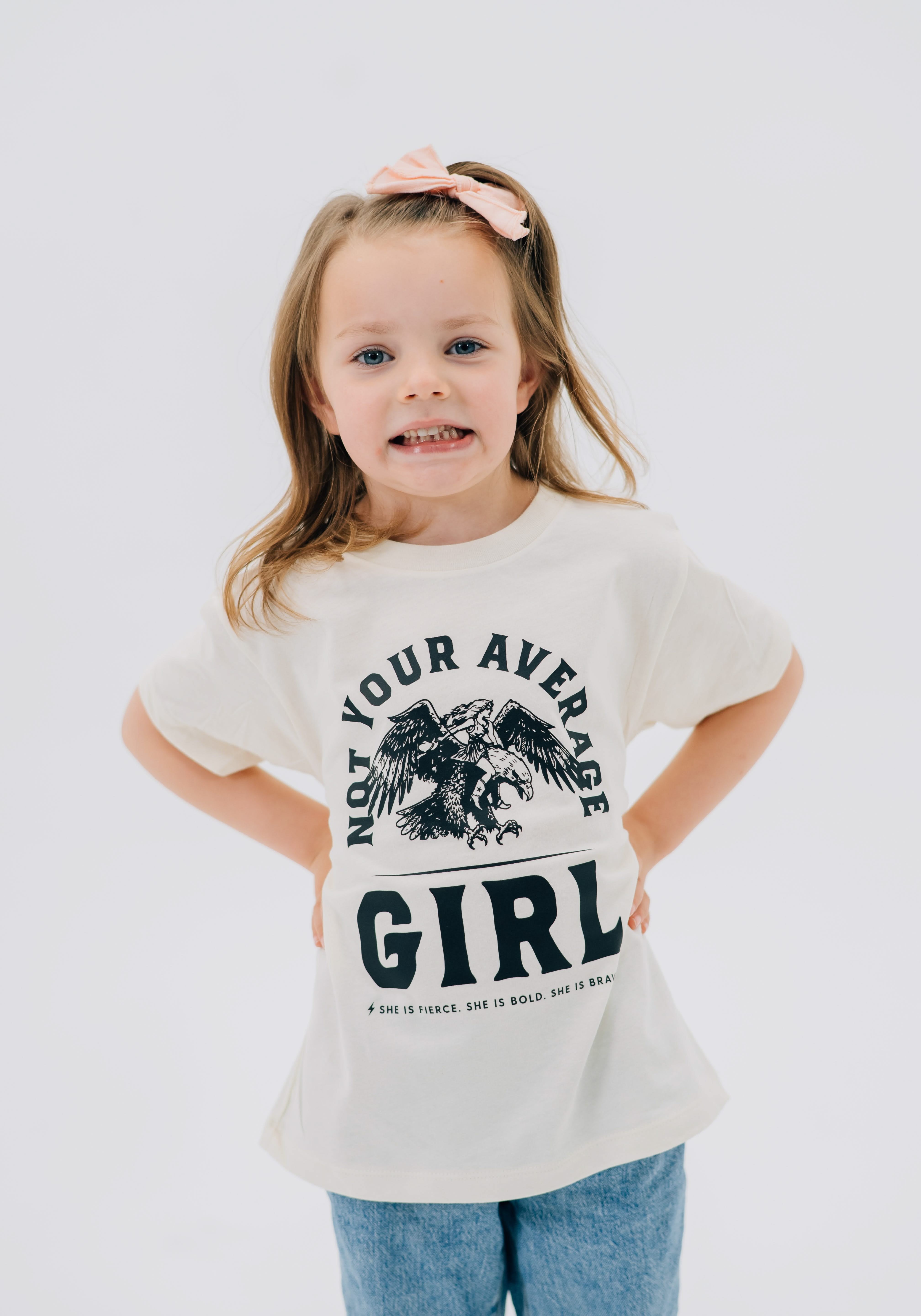 Child tee in natural with "Not Your Average" design on front, shown on model  – Little Mama Shirt Shop