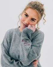 Gray sweater with "Brave, Soft, Strong" embroidered on the sleeve, seen on model - Little Mama Shirt Shop