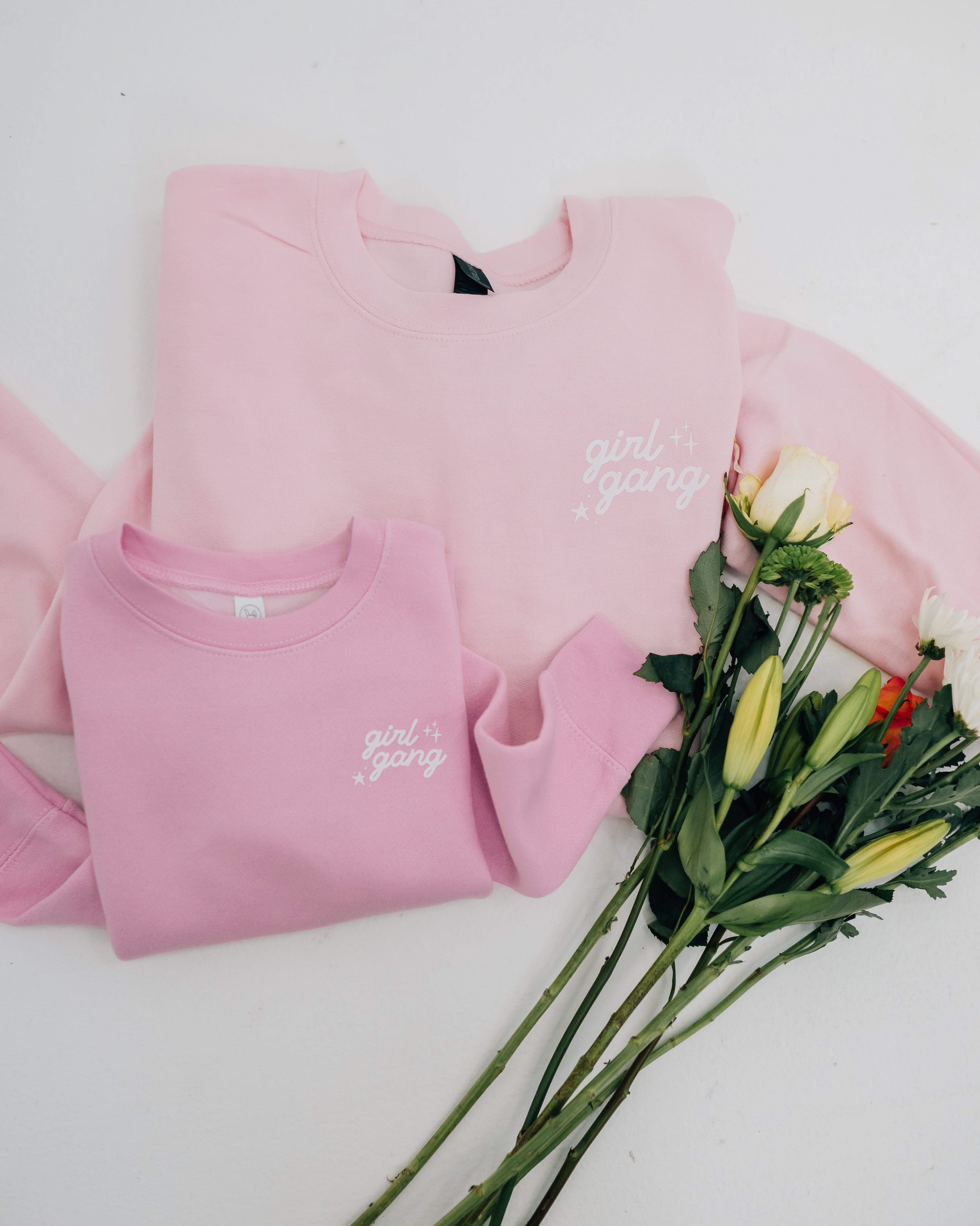 Adult and child sweaters in light pink with "girl gang" design on front chest, shown on flat lay - Little Mama Shirt Shop