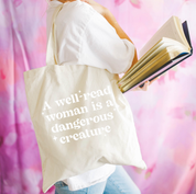 Beige canvas tote bag featuring a 'A well-read woman is a dangerous creature' design on a model - Little Mama Shirt Shop