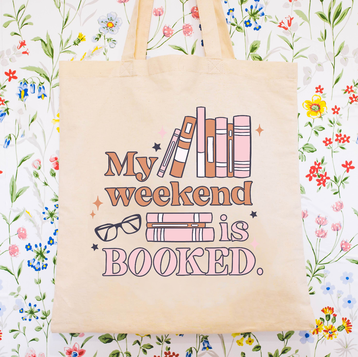 Beige canvas tote bag featuring a 'My weekend is booked' design on a flat lay - Little Mama Shirt Shop