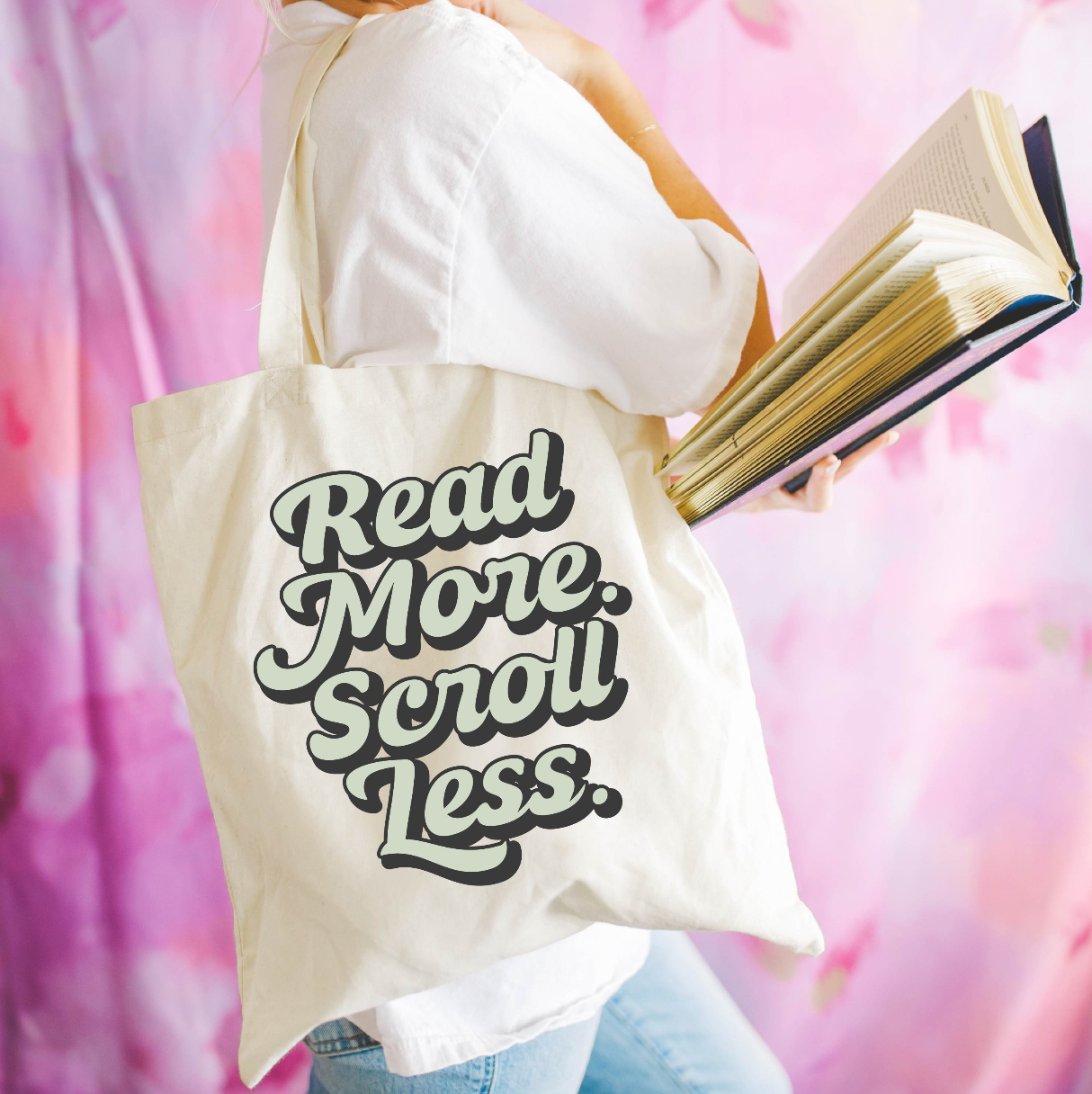 Beige canvas tote bag featuring a 'Read More. Scroll Less.' design on a model - Little Mama Shirt Shop