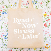 Beige canvas tote bag featuring a 'Read Now Stress Later' design on a flat lay - Little Mama Shirt Shop