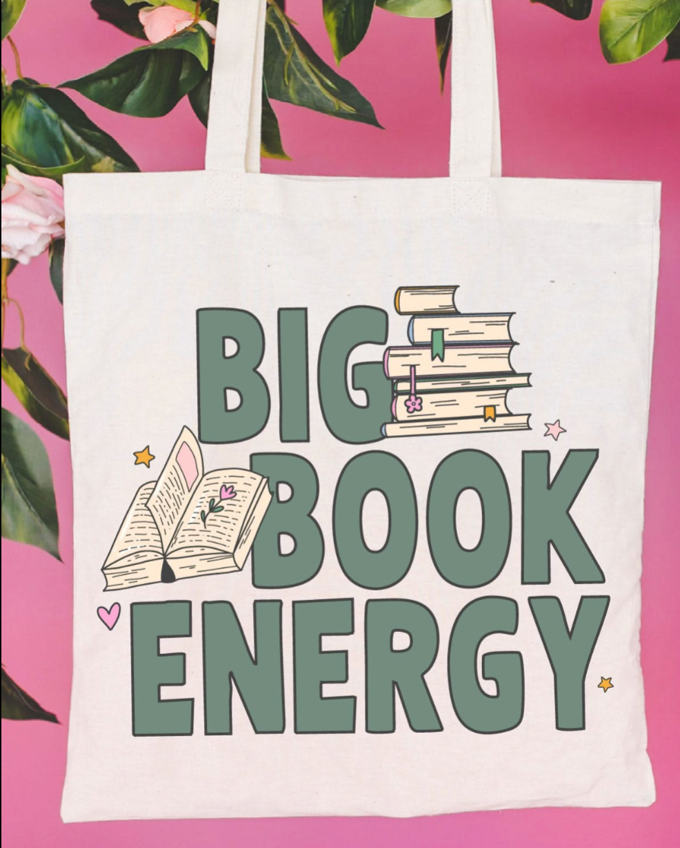 Beige canvas tote bag featuring a &#39;Big Book Energy&#39; design on a flat lay - Little Mama Shirt Shop