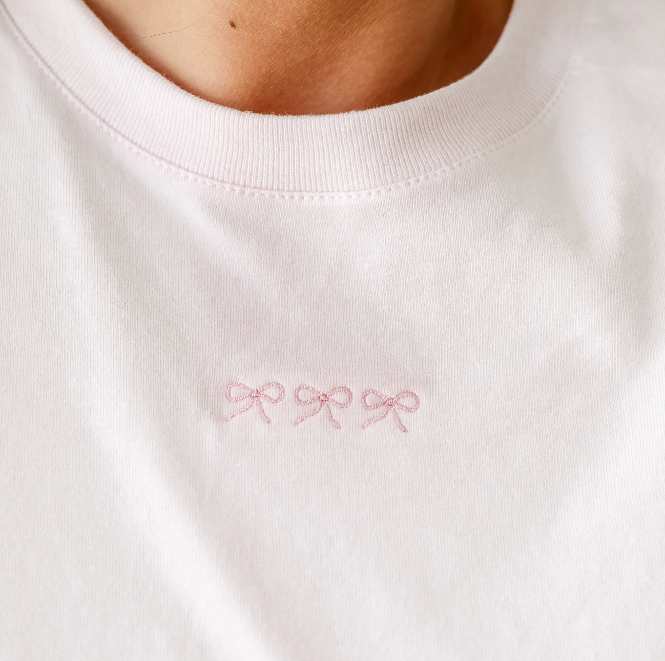 Adult tee in soft pink with mini symbol three bows design on front, shown on model – Little Mama Shirt Shop