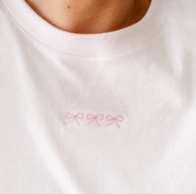 Adult tee in soft pink with mini symbol three bows design on front, shown on model – Little Mama Shirt Shop