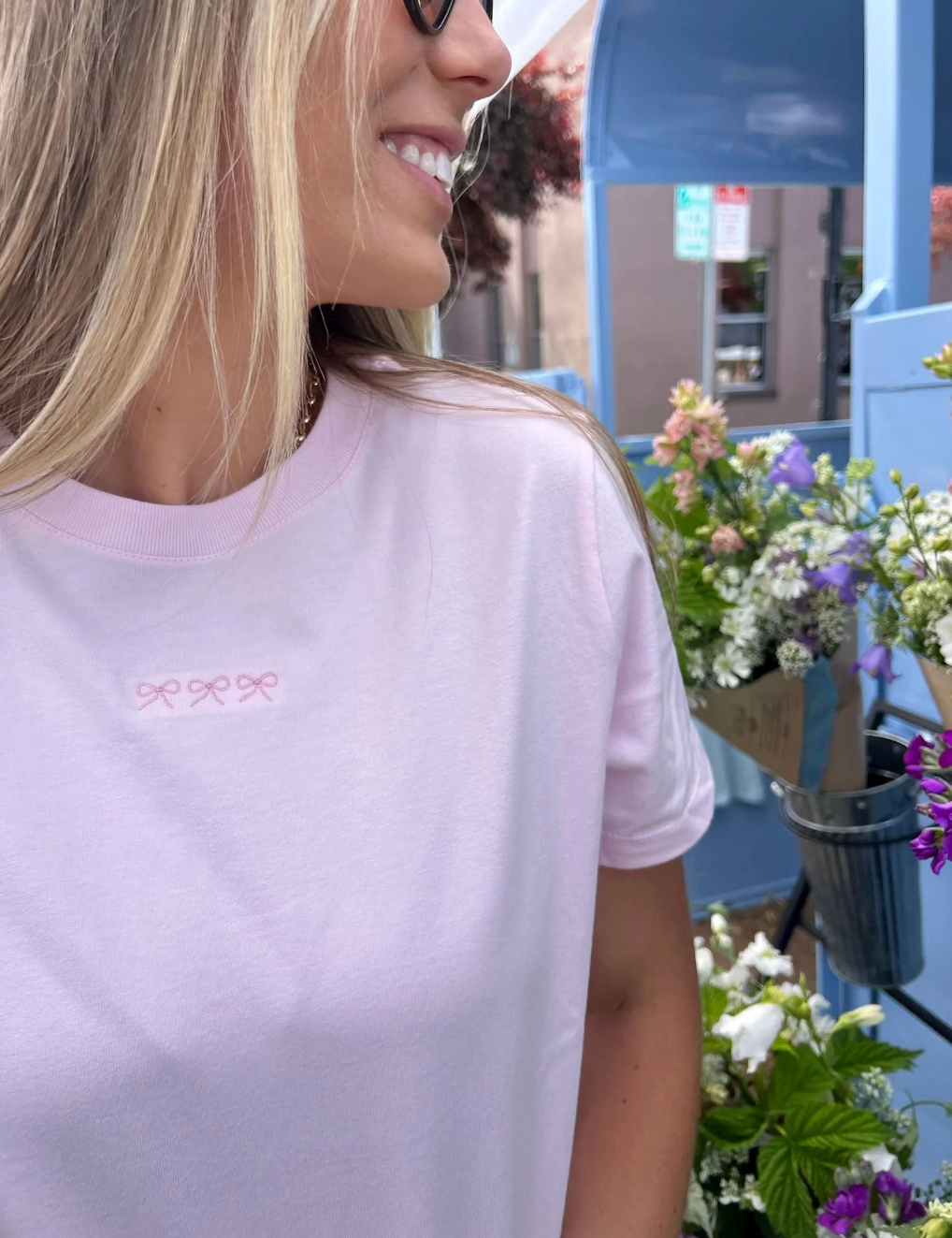 Adult tee in soft pink with mini symbol three bows design on front, shown on model – Little Mama Shirt Shop
