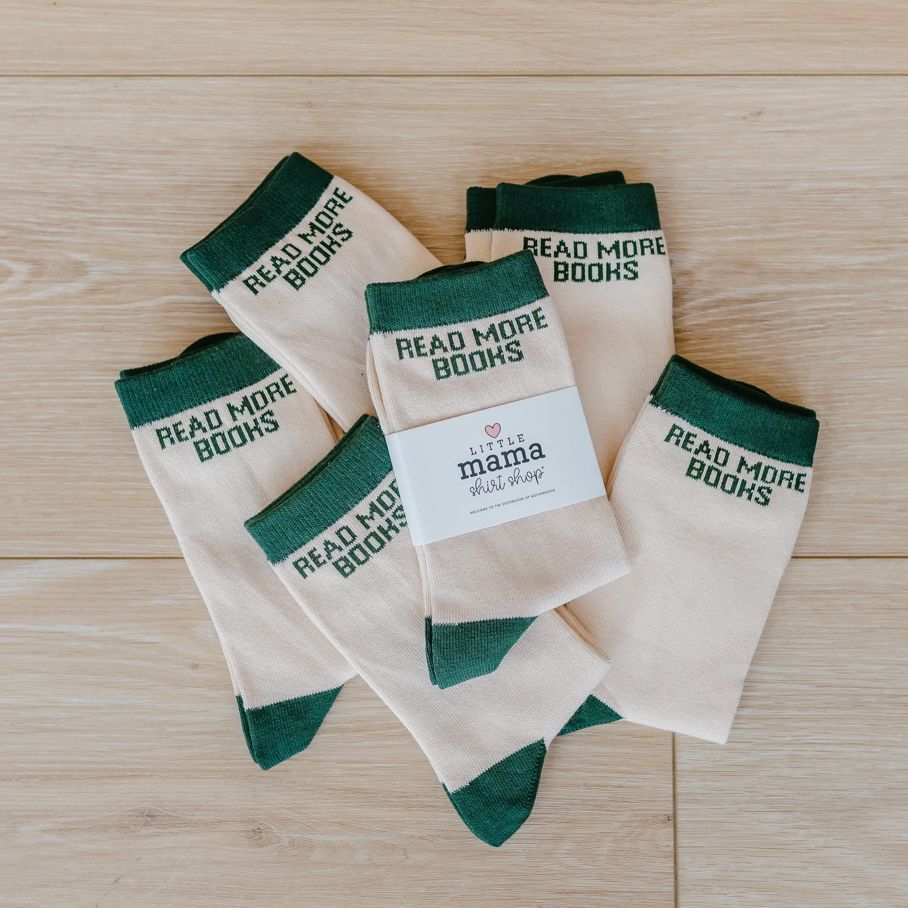 Pair of tan athletic-style socks with green stripe and subtle “Read More Books” text near the cuff. Flat lay picture - Little Mama Shirt Shop