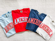 Comfort Colors AMERICA shirts in red, white, and blue with gingham lettering, laid out as a classic summer flat lay