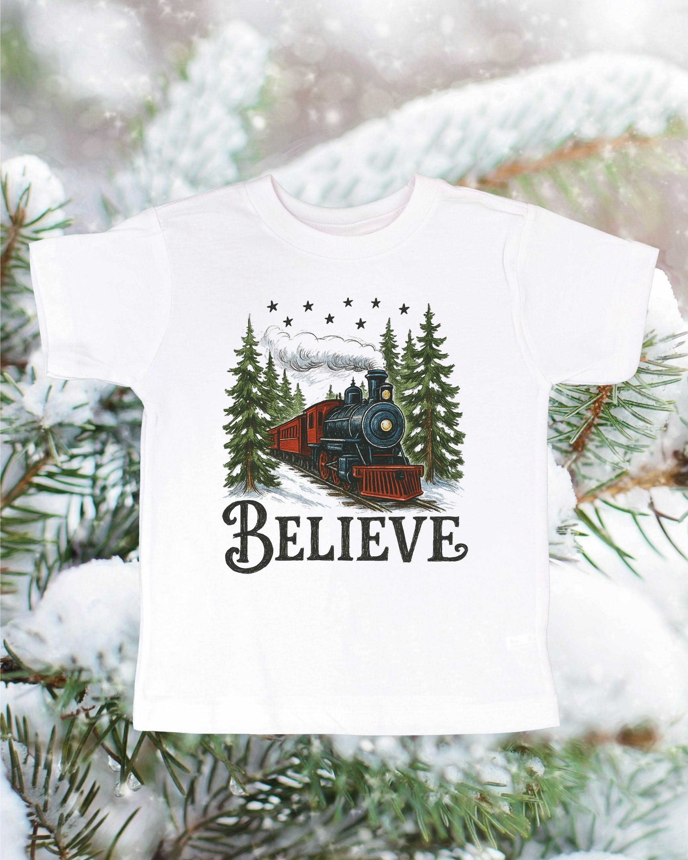 Child tee in white with winter train and &#39;Believe&#39; on chest, shown on flat lay – Little Mama Shirt Shop