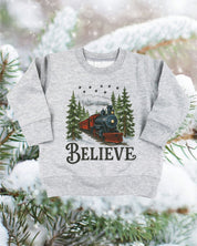 Child sweater in gray with winter train and 'Believe' on chest, shown on flat lay – Little Mama Shirt Shop