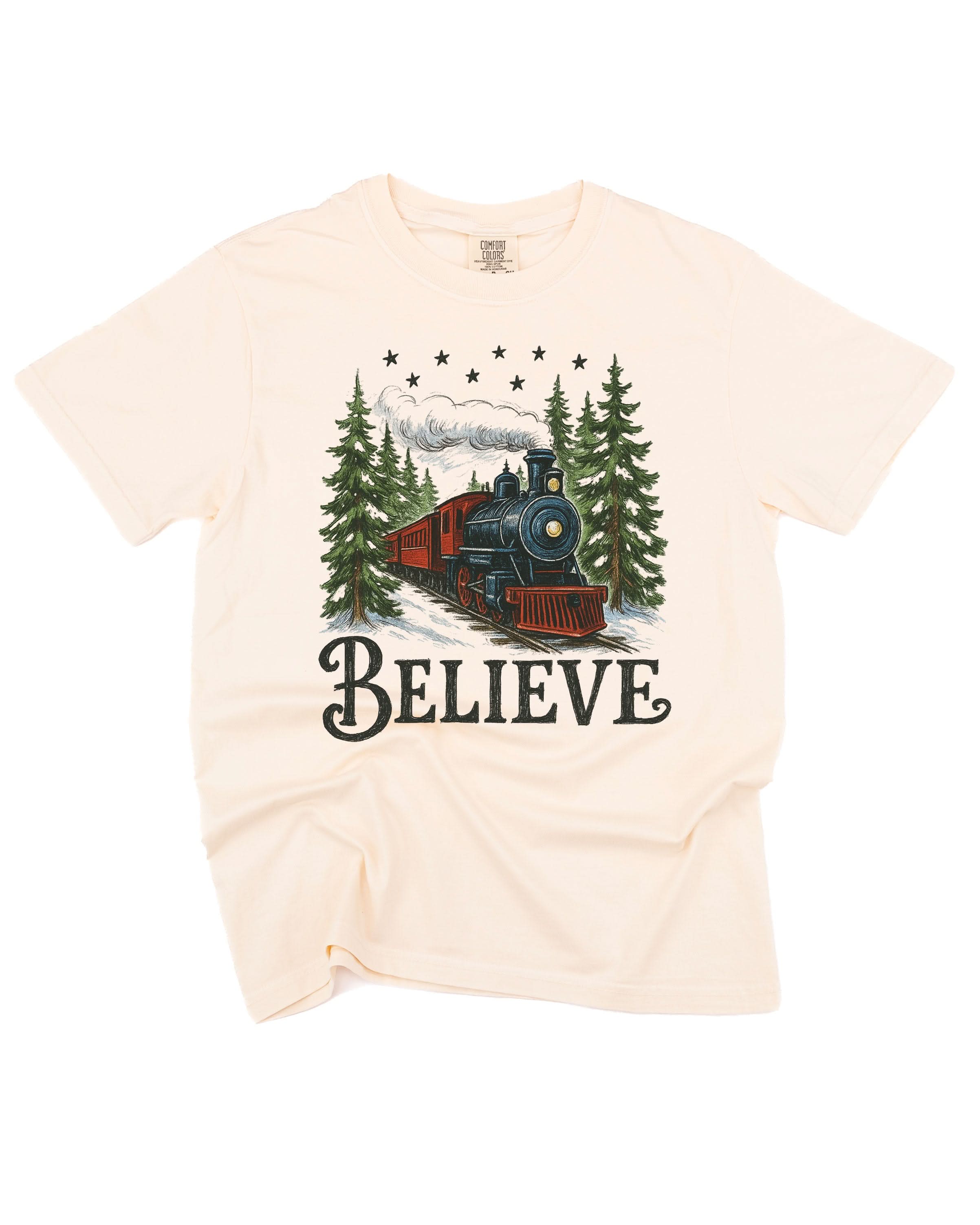 Comfort Colors Tee in Ivory with winter train and 'Believe' on chest, shown on flat lay – Little Mama Shirt Shop