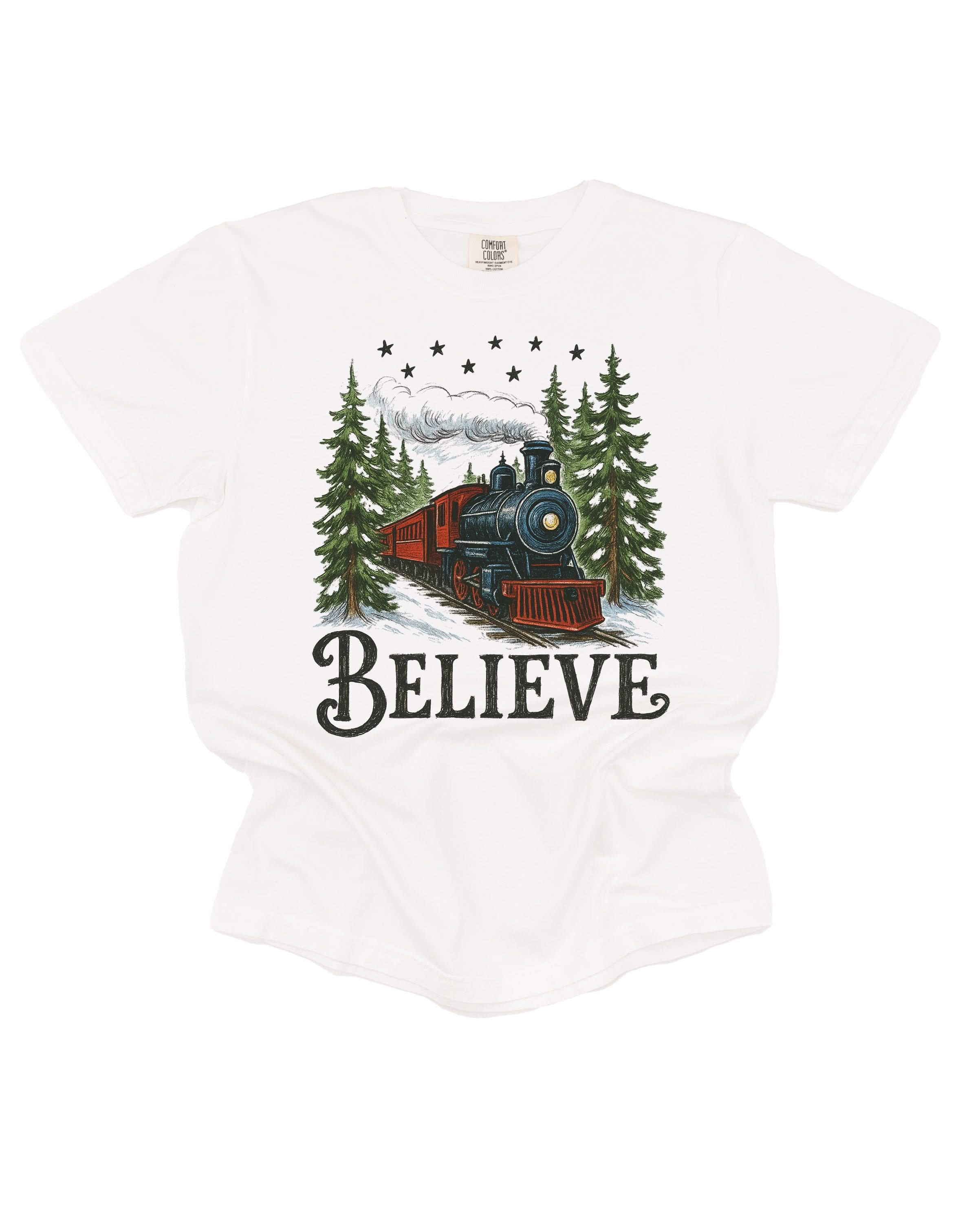 Comfort Colors Tee in white with winter train and 'Believe' on chest, shown on flat lay – Little Mama Shirt Shop