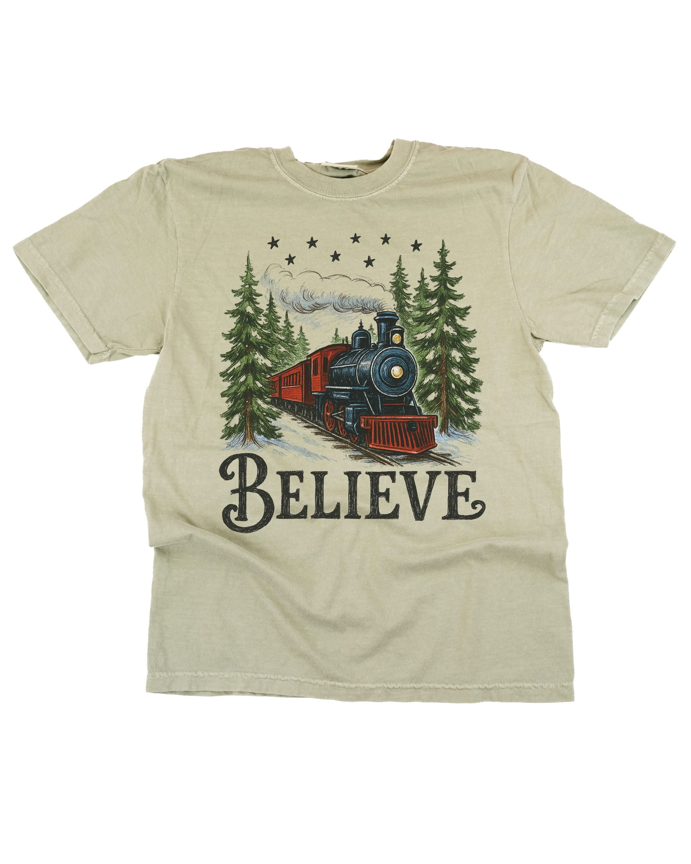 Comfort Colors Tee in sandstone with winter train and 'Believe' on chest, shown on flat lay – Little Mama Shirt Shop