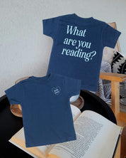 Child tee in navy w/ ice blue detail with a 'book lover' heart graphic on the front and 'What are you reading?' graphic on back, shown on flat lay – Little Mama Shirt Shop