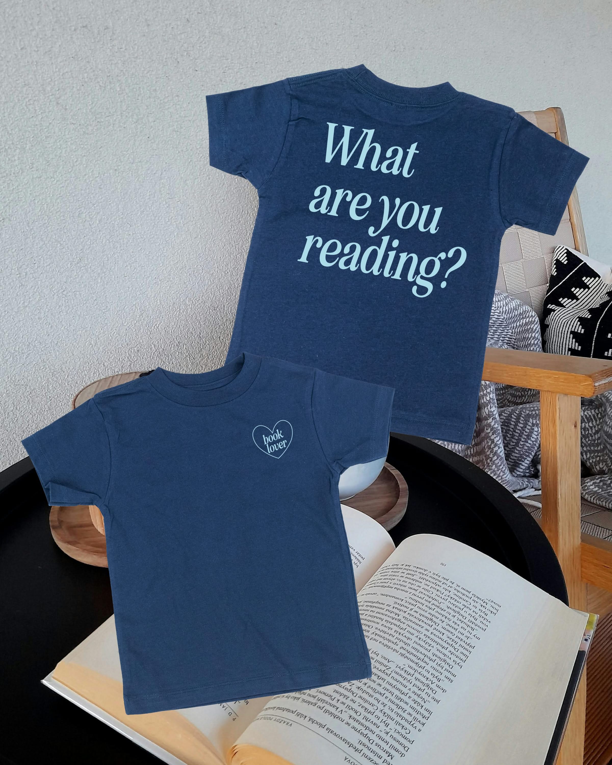  ice blue detail with a 'book lover' heart graphic on the front and 'What are you reading?' graphic on back, shown on flat lay – Little Mama Shirt Shop