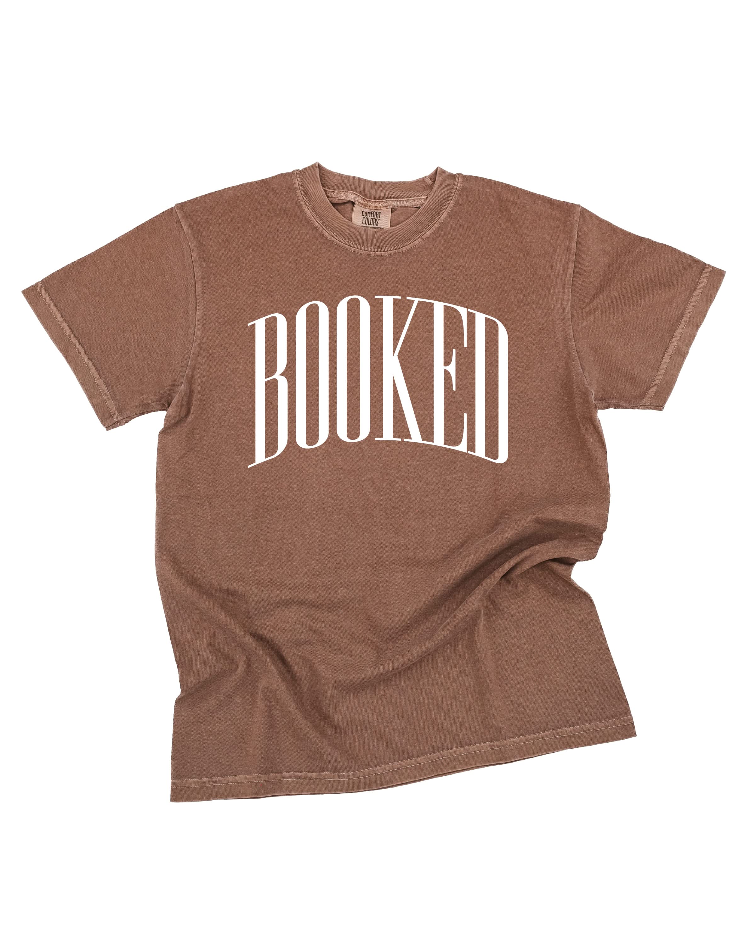 Comfort colors tee in espresso with 'BOOKED' graphic on chest, shown on flat lay – Little Mama Shirt Shop
