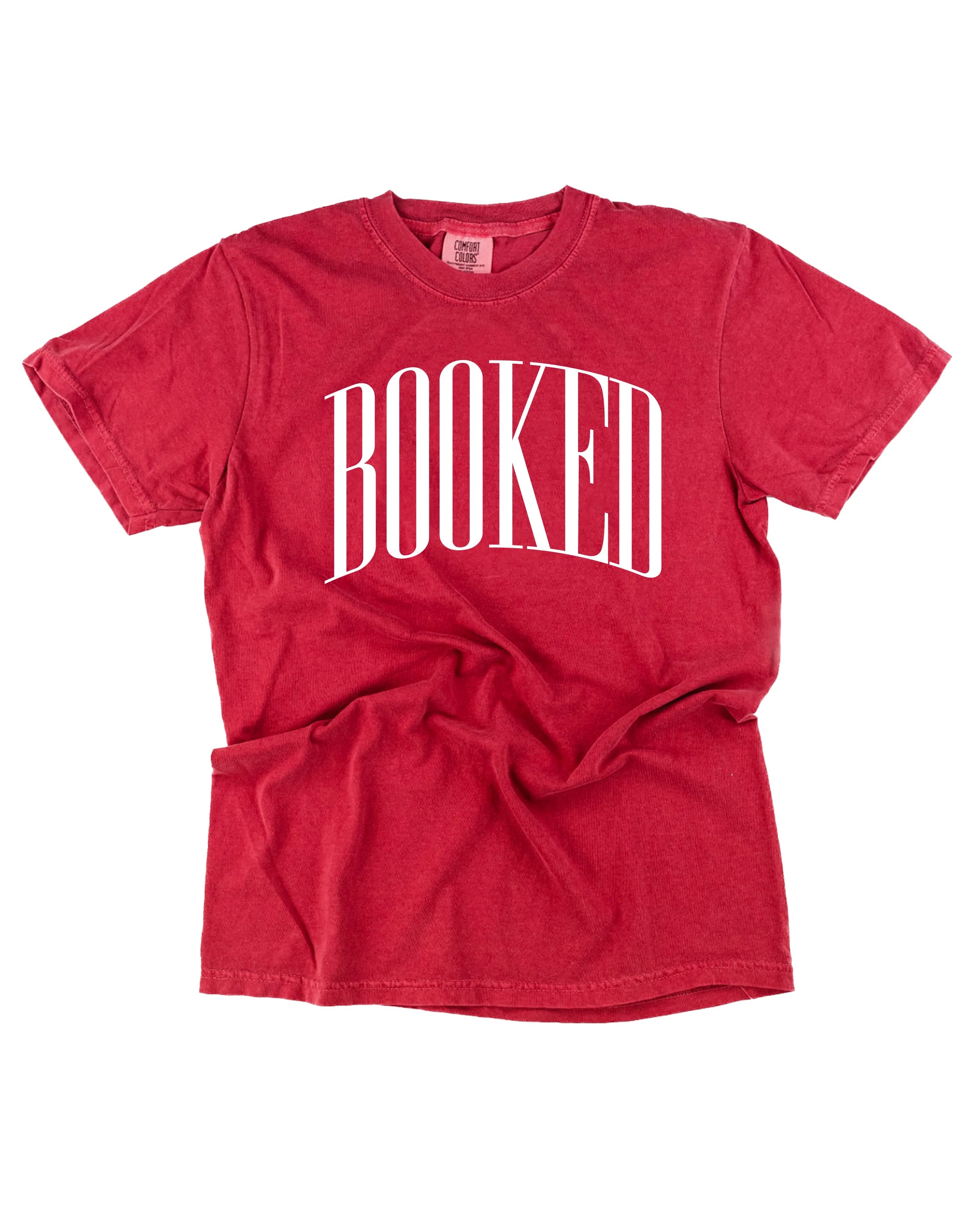 Comfort colors tee in crimson with 'BOOKED' graphic on chest, shown on flat lay – Little Mama Shirt Shop